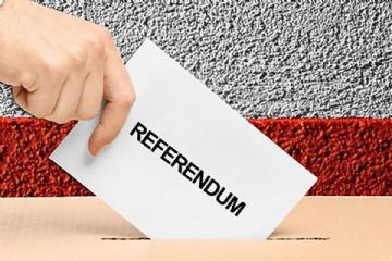 immagine che rappresenta una mano che imbuca un foglio con sopra scritto referendum