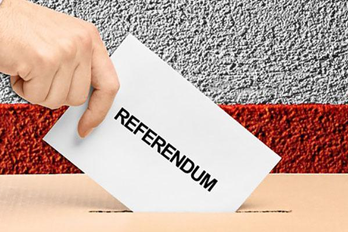 immagine che rappresenta una mano che imbuca un foglio con sopra scritto referendum